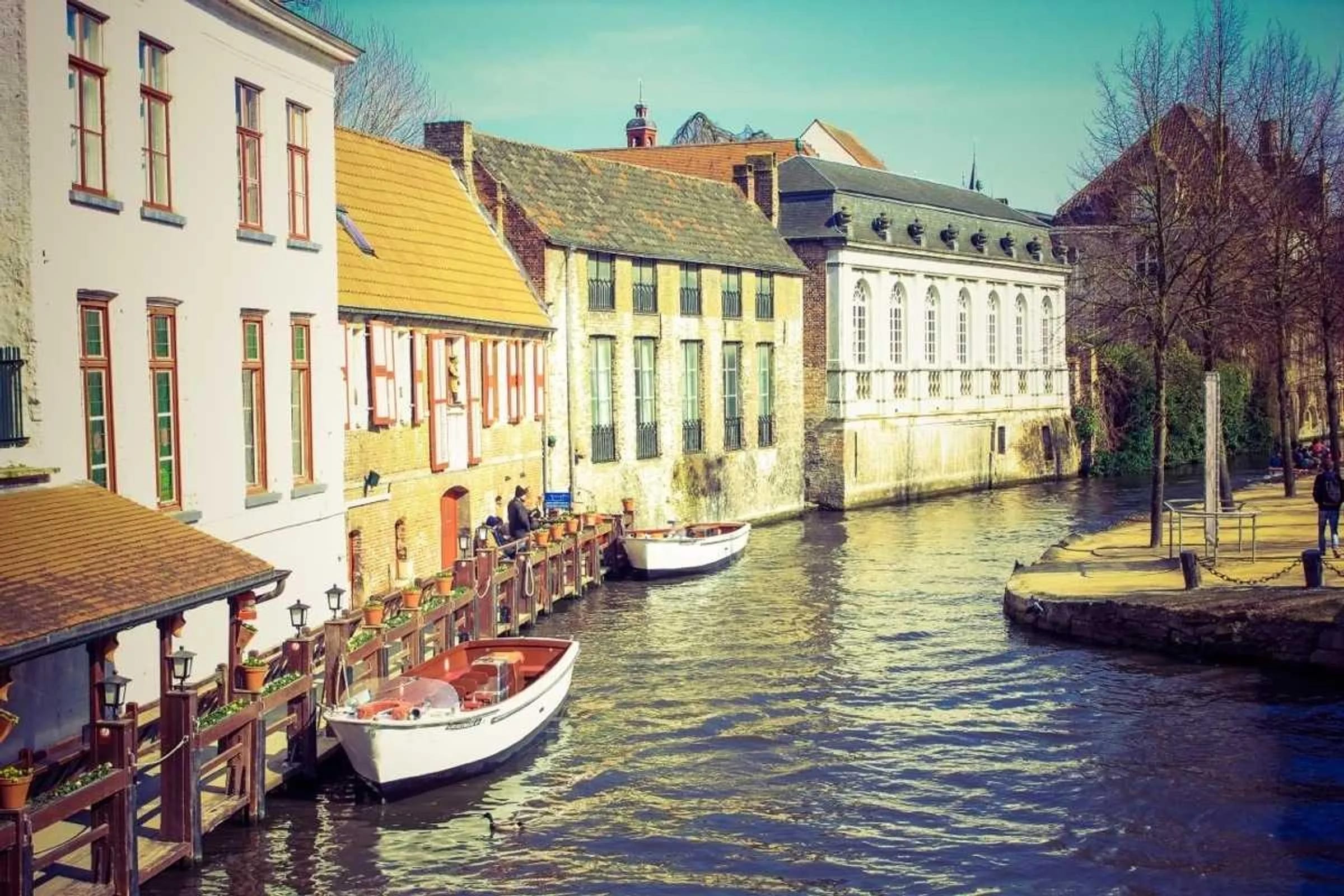 Colourful old townhouses lining a canal with small moored boats.